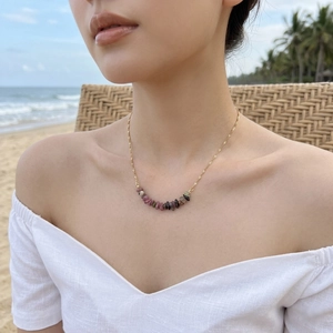 Golden necklace with natural tiger eye beads worn by model on a sunny beach