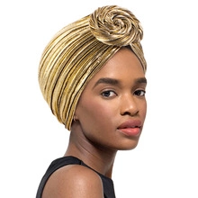 Detailed close-up of metallic gold turban with spiral knot design on model