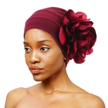 Detailed view of dark red turban hat with large layered 3D floral decoration