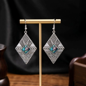 Detail of vintage bohemian silver earrings with abalone shell inlay on black satin background