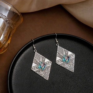 Detail of bohemian rhombus earrings with vintage silver engraving and blue iridescent inlay