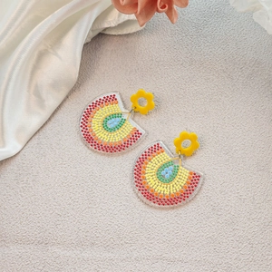 Macro shot of colorful acrylic flower earrings with rainbow rhinestones on silk fabric