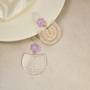 Detail of floral earrings with purple petal studs and semi-circular acrylic charms