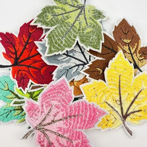Detailed macro shot of multicolored maple leaf embroidered patches on white background.