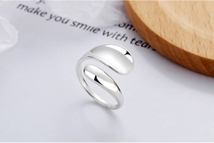 Detail of adjustable S925 sterling silver ring with smooth bean-shaped ends on wooden tray