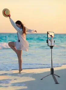 Portable tripod selfie stick with 950mm extension and Bluetooth remote on beach