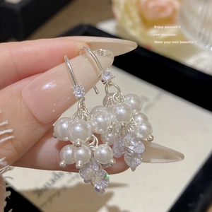 Detailed macro view of long grape-style pearl earrings with shimmering zircon accents