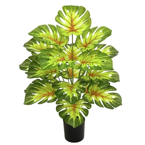 Close-up of artificial Monstera plant with vibrant green leaves in a black pot