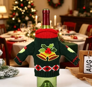 Detail of knitted green Christmas wine bottle cover with bell embroidery and festive collar