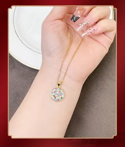 Close-up of gold necklace with a round pendant set with multi-colored gemstones worn on neck