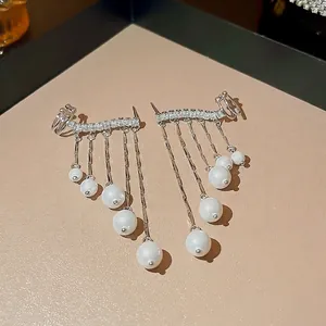 Elegant silver tassel earrings with sparkling zircons and white pearls on beige leather