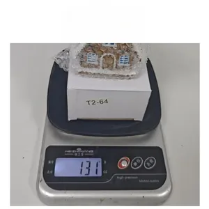 Miniature resin Christmas house with LED lights and snow detail on a shipping scale
