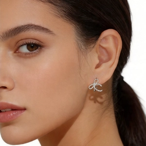 Close-up of elegant s925 silver bow earrings with textured pavé detail on model ear