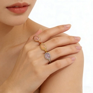 Detail of three oval gemstone rings in rose gold, gold and silver finish with brushed texture
