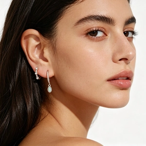 Detail of silver hoop earrings featuring white pearls and oval opal stone drop pendants
