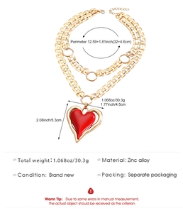 Detail of double-layer gold chain necklace featuring a large red heart pendant in zinc alloy