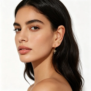 Close-up of elegant gold bow earrings and drop stud set worn by a model on white background
