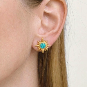 Retro golden sunburst stud earrings with turquoise stone worn by model on ear