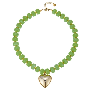 Dettaglio di una collana di perle in resina verde con un grande ciondolo a cuore dorato