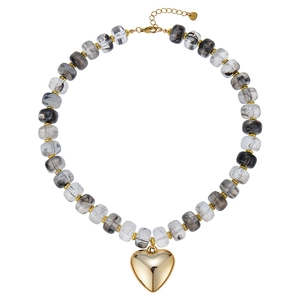 Dettaglio di collana di perle in resina marmorizzata con grande ciondolo a cuore d'oro