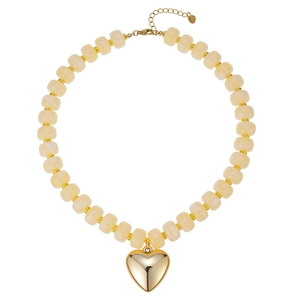 Dettaglio di una collana di perle in resina crema con un grande ciondolo a cuore dorato lucido.