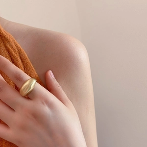 Close-up of a matte gold chunky pebble ring featuring a minimalist curved dome design
