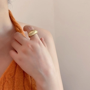 Macro shot of a chunky matte gold wide band ring with a curved organic design for women