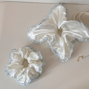 Detailed view of white satin hair scrunchies with elegant blue lace trim and pearl accents