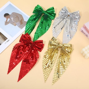 Macro shot of glitter bow hair clips with long ribbons in red, green, gold, and silver colors