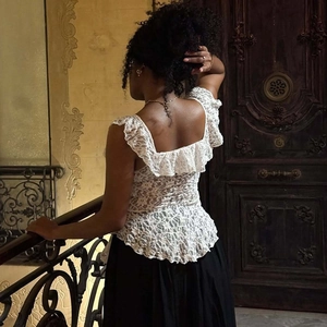Detailed back view of white lace blouse featuring ruffles and floral embroidery