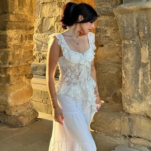 Close-up of white bohemian lace sleeveless top with delicate ruffles and drawstring neckline