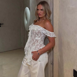 Detail of white lace off-shoulder top showing intricate floral hollow textures and ruffles