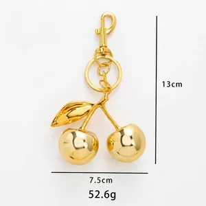 Portachiavi a ciliegia in metallo dorato, dimensioni 13x7,5 cm e peso 52,6 g su sfondo bianco