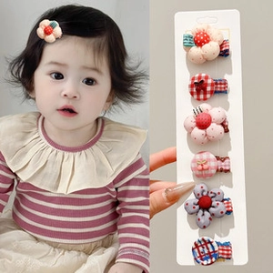 Dettaglio di un set di 6 fermagli in tessuto per bambine con fiori e motivi carini