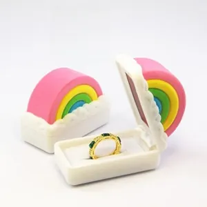 Macro shot of an open rainbow-shaped jewelry box with a gold ring and green gemstone