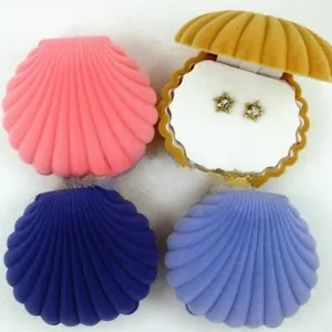 Detail of shell-shaped velvet jewelry boxes in four colors showing a pair of star earrings