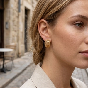 Close-up of 18K gold plated hollow lattice earrings worn by a model in soft daylight