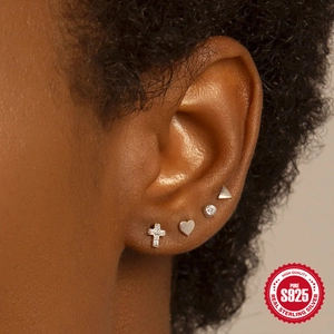 Close-up of S925 sterling silver mini earring set with zircon cross and heart on ear
