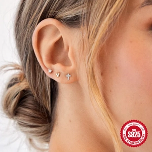 Close-up of S925 sterling silver stud earring set with cross and zircon on ear
