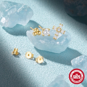 Detailed view of S925 sterling silver gold-plated stud earrings set on blue crystal props
