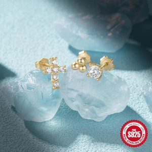 Macro shot of S925 sterling silver gold stud earrings set with cross and zircon details