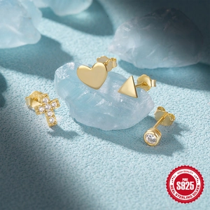 Detail of four gold S925 sterling silver stud earrings with zirconia on blue crystal props