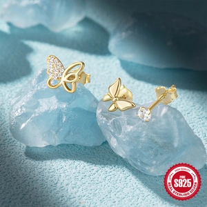Detail view of S925 silver gold butterfly and cubic zirconia stud earring set on blue crystal