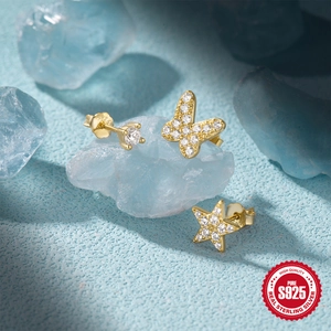 Macro detail of S925 sterling silver gold earrings set with star, butterfly and zircon