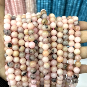 Macro view of natural pink opal round beads with black mineral inclusions for jewelry making