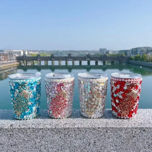 Outdoor display of four rhinestone vacuum flasks with golden peacock designs