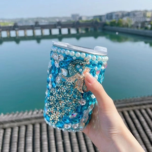 Detail of blue stainless steel cup with peacock rhinestone inlay and white faux pearls