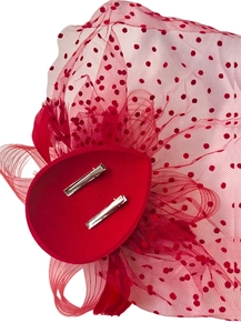 Close-up of red fascinator hat featuring mesh netting, feathers, and dual silver metal clips