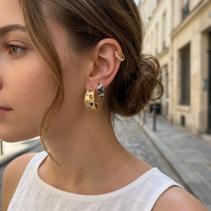 Close-up of elegant gold earrings set with colorful crystals and blue stones on model