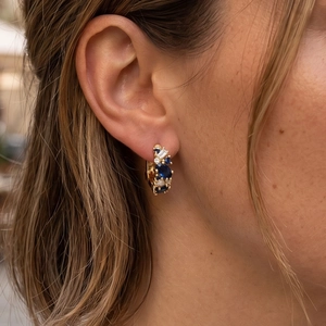 Detail of vintage gold hoop earrings with deep blue oval stones and sparkling clear diamonds